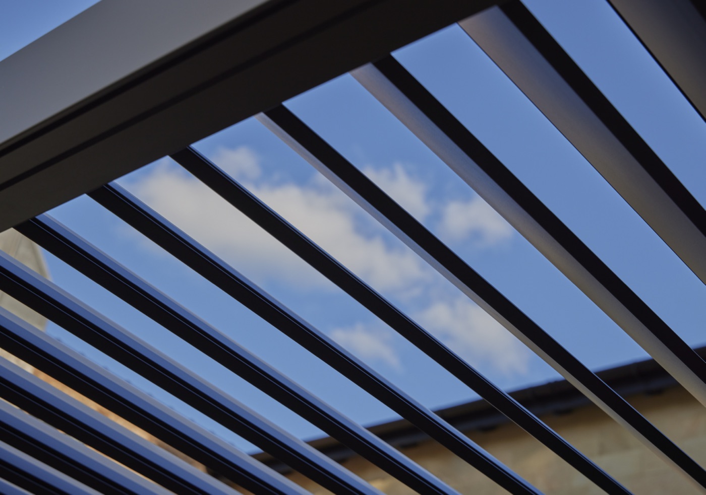 Powder-coated aluminium louvres seen from below against a blue sky
