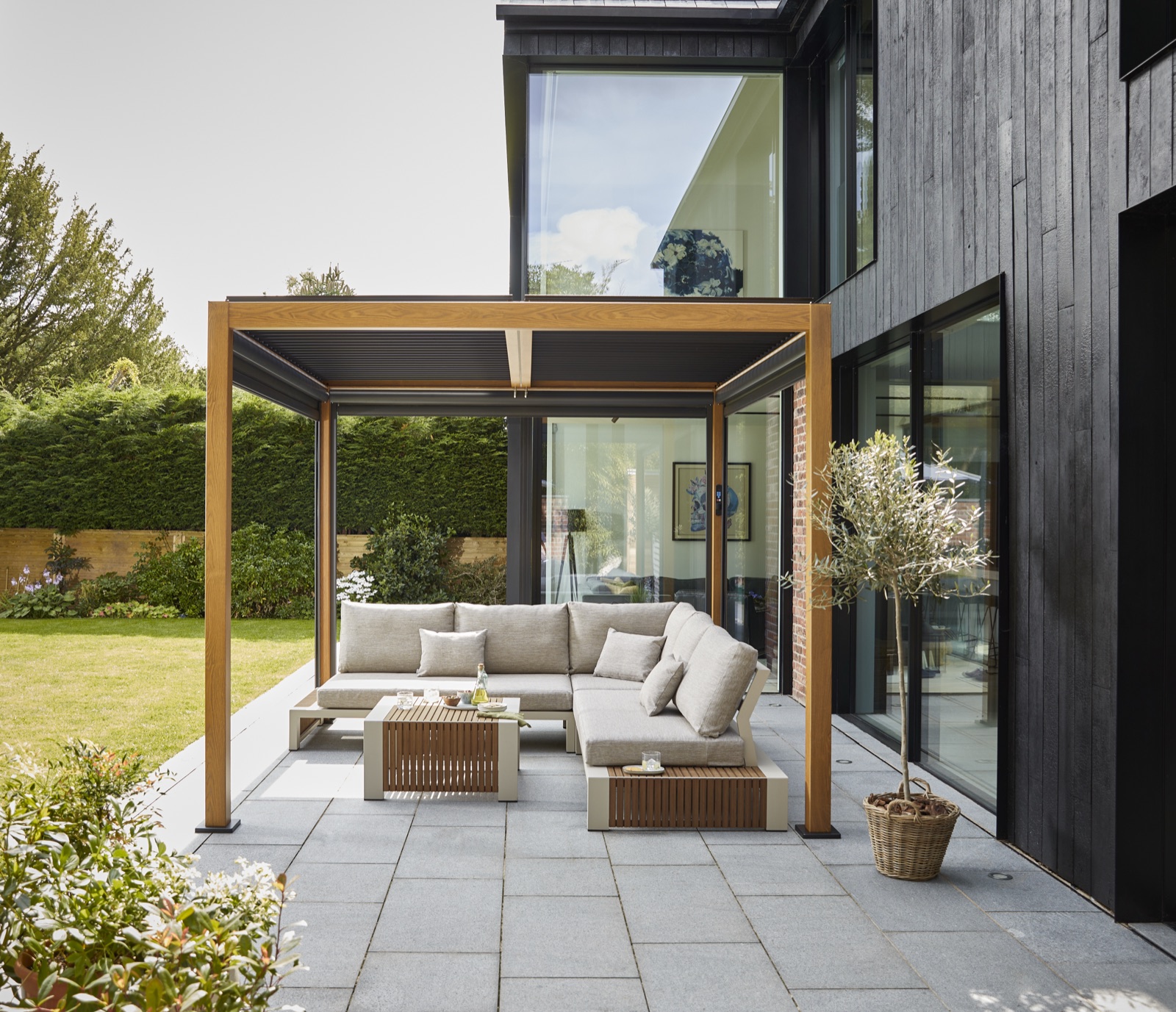 Wood-look Royce Cube pergola fully open in a landscaped garden